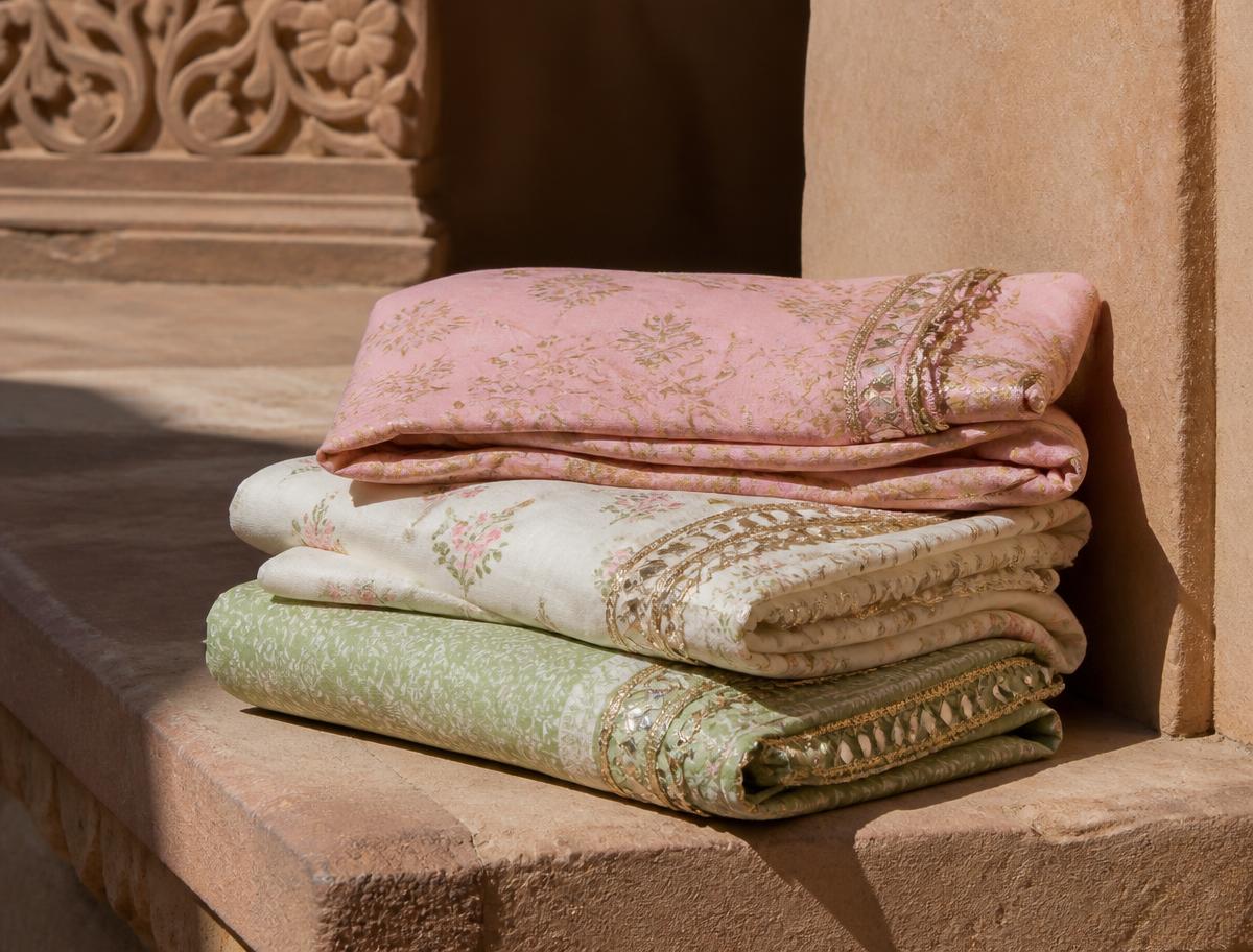 Folded pink, ivory and sage printed fabrics on a sandstone ledge